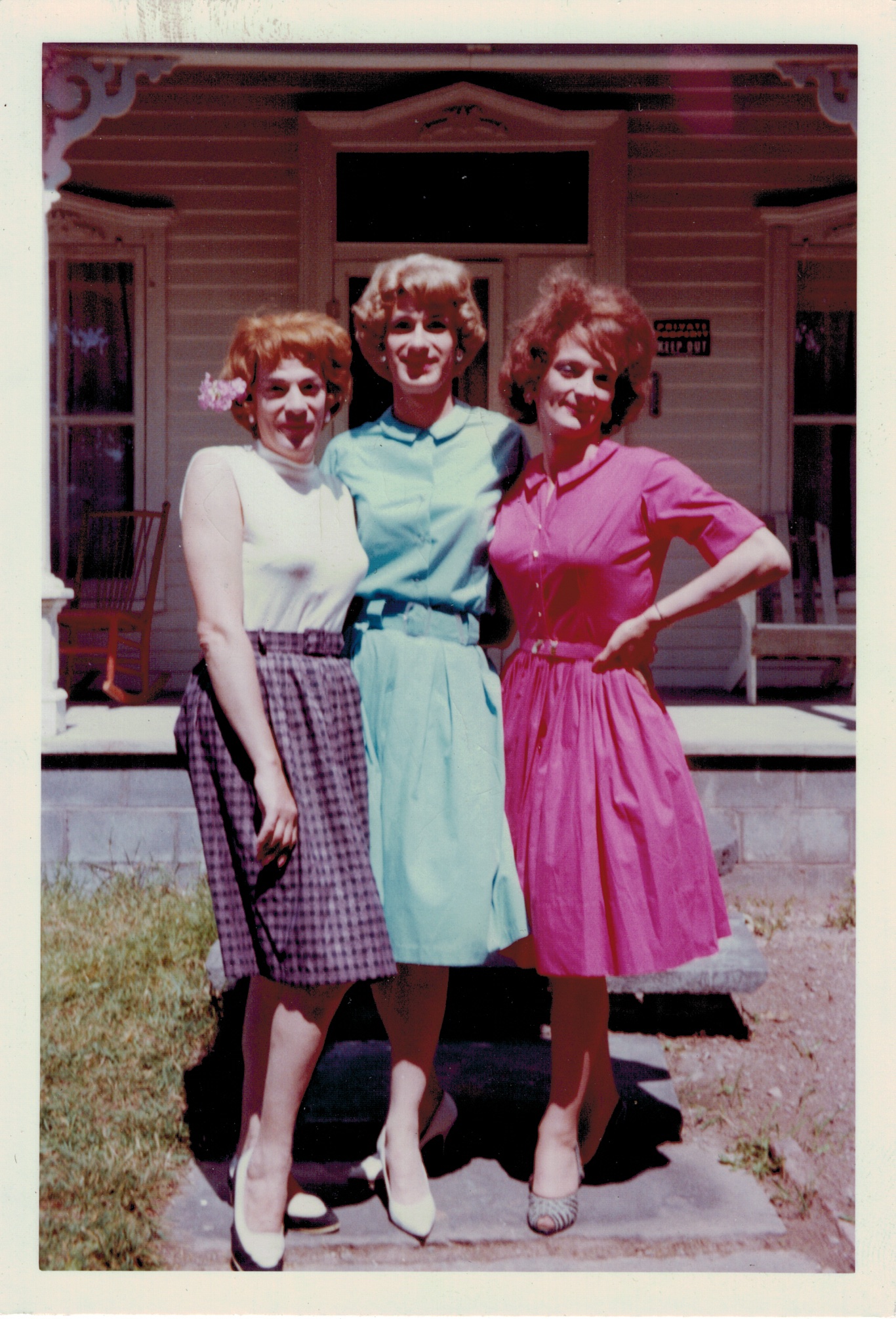 Drie vrouwen gekleed in jaren '50-'60 jurken poseren innig gearmd met elkaar. Het zijn mannen die met veel plezier in travestie lopen en elkaar daarbij steunen.